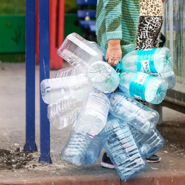 Woman carrying multiple plastic water cans